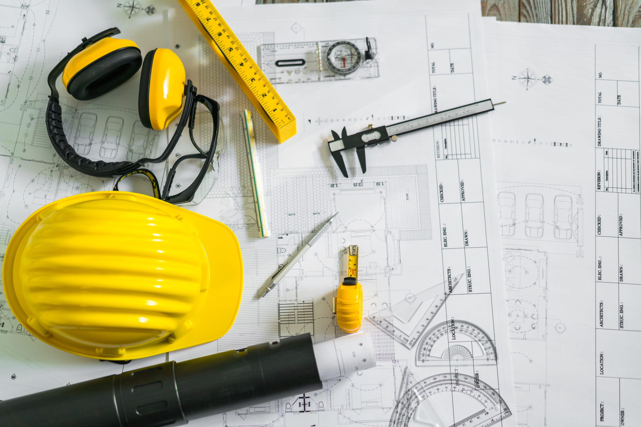 Construction plans with helmet and drawing tools on blueprints